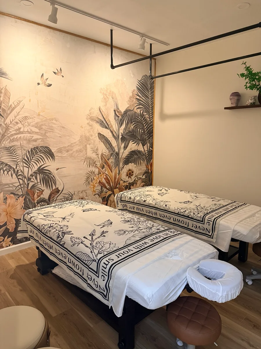 The couples room at Diamond Massage, two tables made up side by side beneath a painted botanical mural