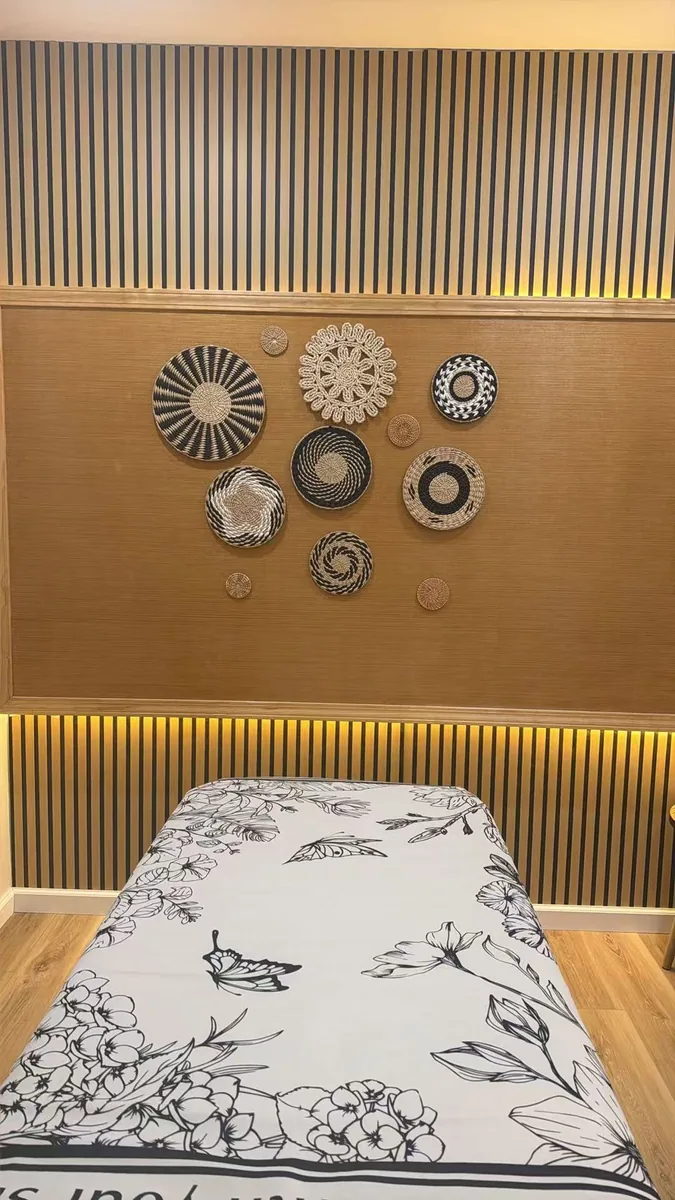 A treatment room with woven baskets on the wall above a floral-sheeted table